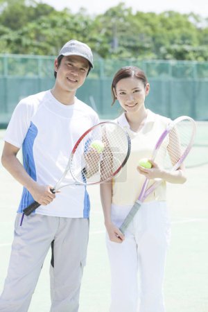 Photo for Young couple playing tennis outdoors - Royalty Free Image