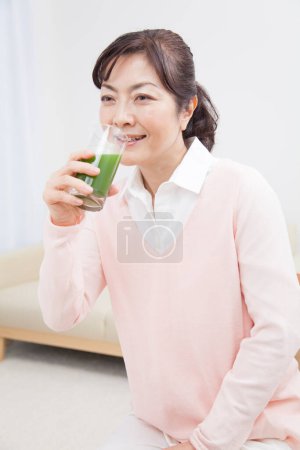 Foto de Mujer asiática con un vaso de jugo verde - Imagen libre de derechos