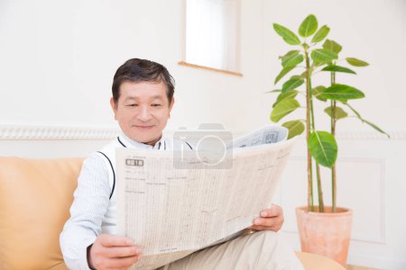 Téléchargez les photos : Homme lisant le journal à la maison - en image libre de droit
