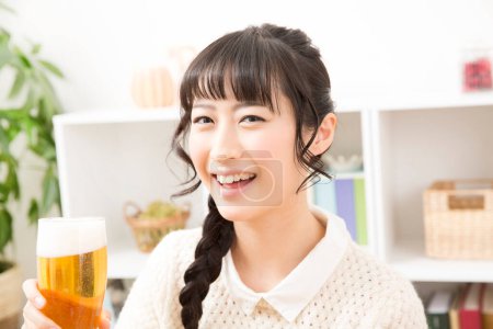 Foto de Mujer asiática sosteniendo una cerveza en casa - Imagen libre de derechos