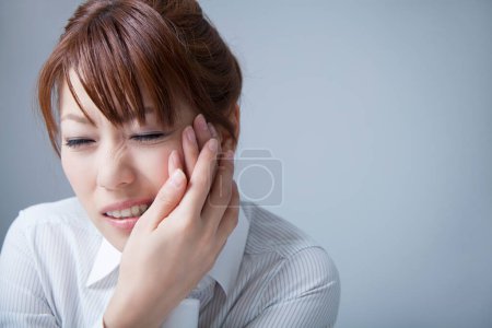 Photo for Portrait of young asian businesswoman having tooth ache on light grey background - Royalty Free Image