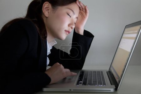 Téléchargez les photos : Jeune femme d'affaires fatiguée avec ordinateur portable au bureau - en image libre de droit