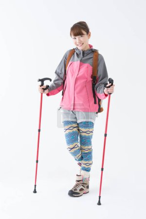 Téléchargez les photos : Portrait studio de femme japonaise souriante marchant avec des bâtons de marche nordique - en image libre de droit