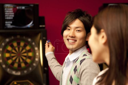 Photo for Young Japanese couple playing darts game - Royalty Free Image