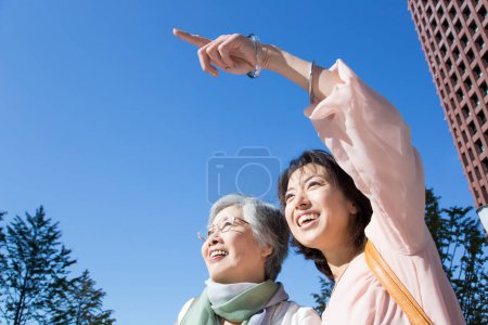 Photo for Happy senior and mature japanese women against blue sky - Royalty Free Image