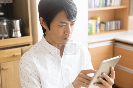 Téléchargez les photos : Homme d'affaires utilisant une tablette numérique à la maison - en image libre de droit