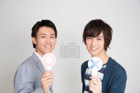 Téléchargez les photos : Portrait de deux beaux jeunes Japonais avec croix et cercles sur fond clair - en image libre de droit