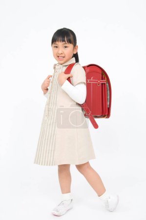 Téléchargez les photos : Portrait studio de mignonne fille japonaise avec sac à dos - en image libre de droit