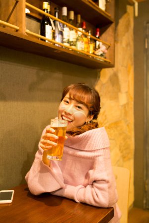 Photo for Young Japanese woman with glass of beer in bar - Royalty Free Image