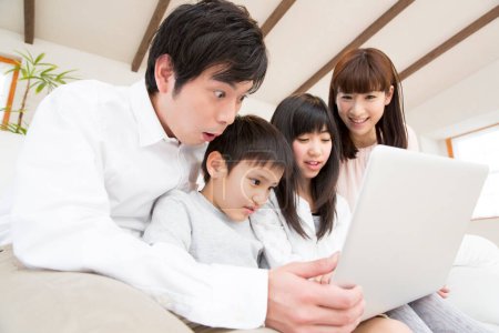 Foto de Retrato de la familia japonesa feliz con el ordenador portátil en casa - Imagen libre de derechos