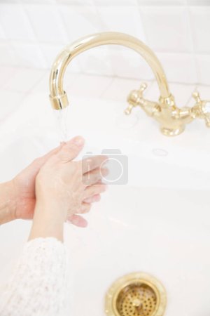 Téléchargez les photos : Femme se lave les mains dans la cuisine - en image libre de droit