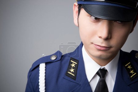 Photo for Studio portrait of Japanese police officer in uniform on grey background - Royalty Free Image