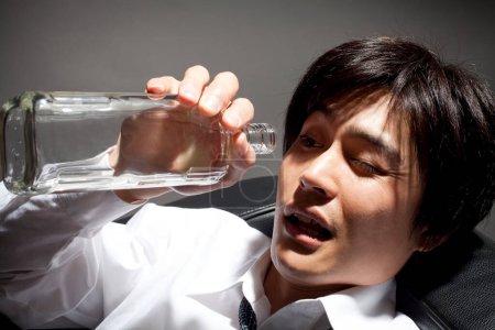 Téléchargez les photos : Asiatique homme d'affaires avec vide bouteille, alcoolique - en image libre de droit