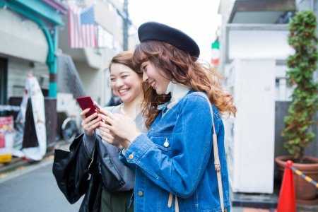 Téléchargez les photos : Femmes asiatiques utilisant téléphone mobile sur la rue - en image libre de droit