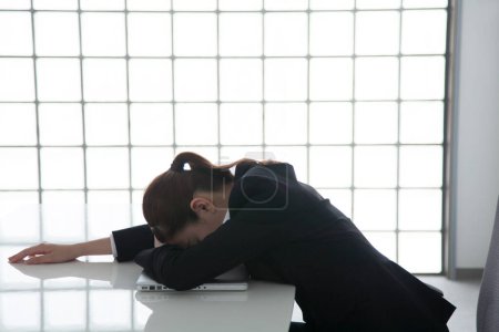 Téléchargez les photos : Portrait de belle jeune femme d'affaires japonaise dormant sur le lieu de travail - en image libre de droit