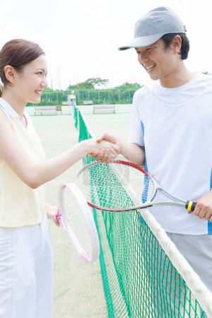 Foto de Pareja estrechando las manos después de jugar al tenis en la corte - Imagen libre de derechos