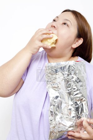 Téléchargez les photos : Gros plan femme en surpoids manger des croustilles - en image libre de droit