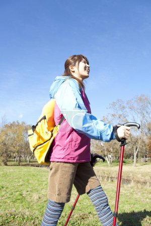 Photo for Young Japanese woman with yellow backpack trekking in autumnal park - Royalty Free Image