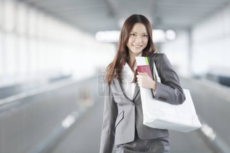 Photo for Portrait of young businesswoman with passport  in airport terminal - Royalty Free Image