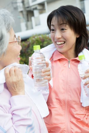 Téléchargez les photos : Deux femmes tenant des bouteilles d'eau et souriant - en image libre de droit