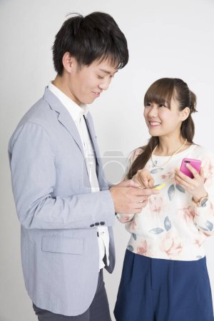 Photo for Asian man and woman with smartphones, studio shot - Royalty Free Image