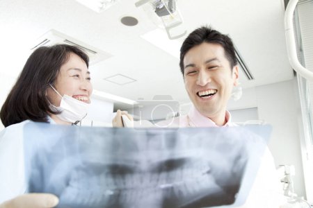 Téléchargez les photos : Dentiste montrant les dents radiographie au patient - en image libre de droit