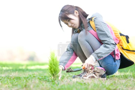Téléchargez les photos : Jeune femme plantant un arbre dans la forêt - en image libre de droit