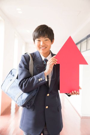 Junger japanischer Student in Uniform mit rotem Pfeil