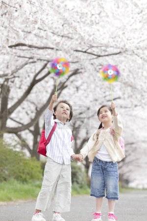 feliz japonés colegiales con molinillos en primavera parque