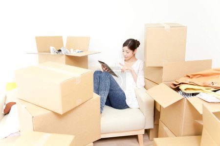 Photo for Woman sitting with tablet with boxes around her - Royalty Free Image