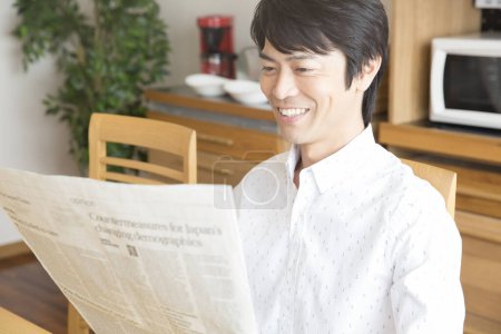Foto de Asiático hombre leyendo periódico en casa - Imagen libre de derechos