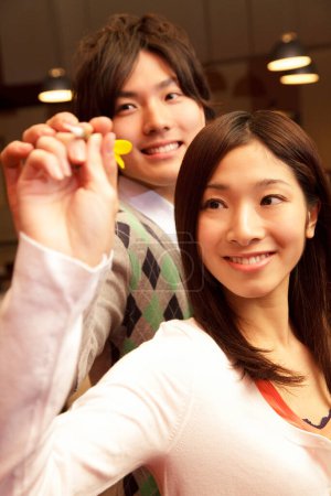 Téléchargez les photos : Jeune couple japonais jouer jeu de fléchettes - en image libre de droit