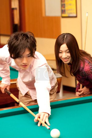 Photo for Happy Japanese young man and woman playing billiard - Royalty Free Image