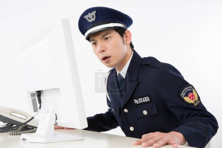 Téléchargez les photos : Portrait studio d'un policier japonais avec ordinateur - en image libre de droit