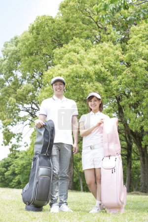 Téléchargez les photos : Asiatique couple tenant golf sacs - en image libre de droit