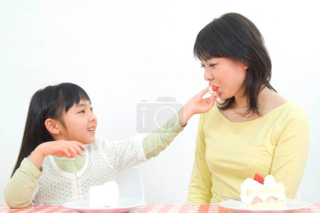 Foto de Pequeña japonesa y su madre comiendo delicioso pastel - Imagen libre de derechos