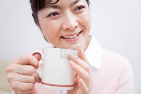 Téléchargez les photos : Asiatique senior dame boire thé - en image libre de droit