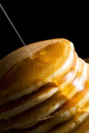Photo for Close up view of delicious pancakes with honey on black background - Royalty Free Image