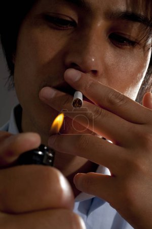 Photo for Asian man smoking a cigarette, studio shot - Royalty Free Image