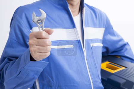 Photo for Man in a blue shirt  with a wrench on a white isolated background - Royalty Free Image