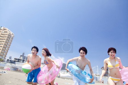 Téléchargez les photos : Jeunes amis s'amusant avec des anneaux gonflables sur la plage - en image libre de droit