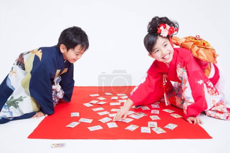 Foto de Niños con ropa tradicional están sentados en el suelo jugando a las cartas - Imagen libre de derechos