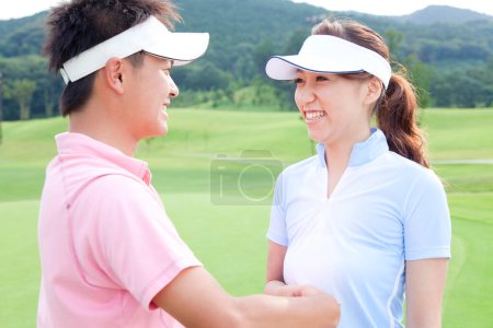 Téléchargez les photos : Couple secouant les mains sur le parcours de golf - en image libre de droit