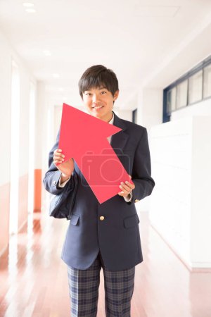 Junger japanischer Student in Uniform mit rotem Pfeil