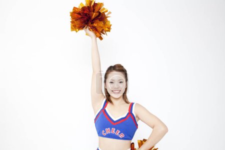 Photo for Beauty Japanese cheerleader dancing at studio. Closeup portrait of beauty young woman lifting pom poms - Royalty Free Image