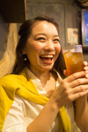 Téléchargez les photos : Portrait de femme japonaise souriante avec boisson dans un café - en image libre de droit