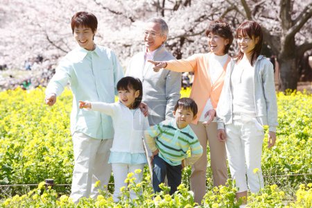 Photo for Outdoor full length portrait of big cheerfull asian family posing against blooming trees - Royalty Free Image