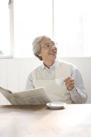 Photo for Mature asian man drinking coffee and reading newspaper - Royalty Free Image
