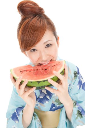 Photo for Beautiful japanese woman in kimono eating watermelon isolated on white - Royalty Free Image