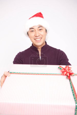 Foto de Asiático hombre en santa claus sombrero holding presente - Imagen libre de derechos